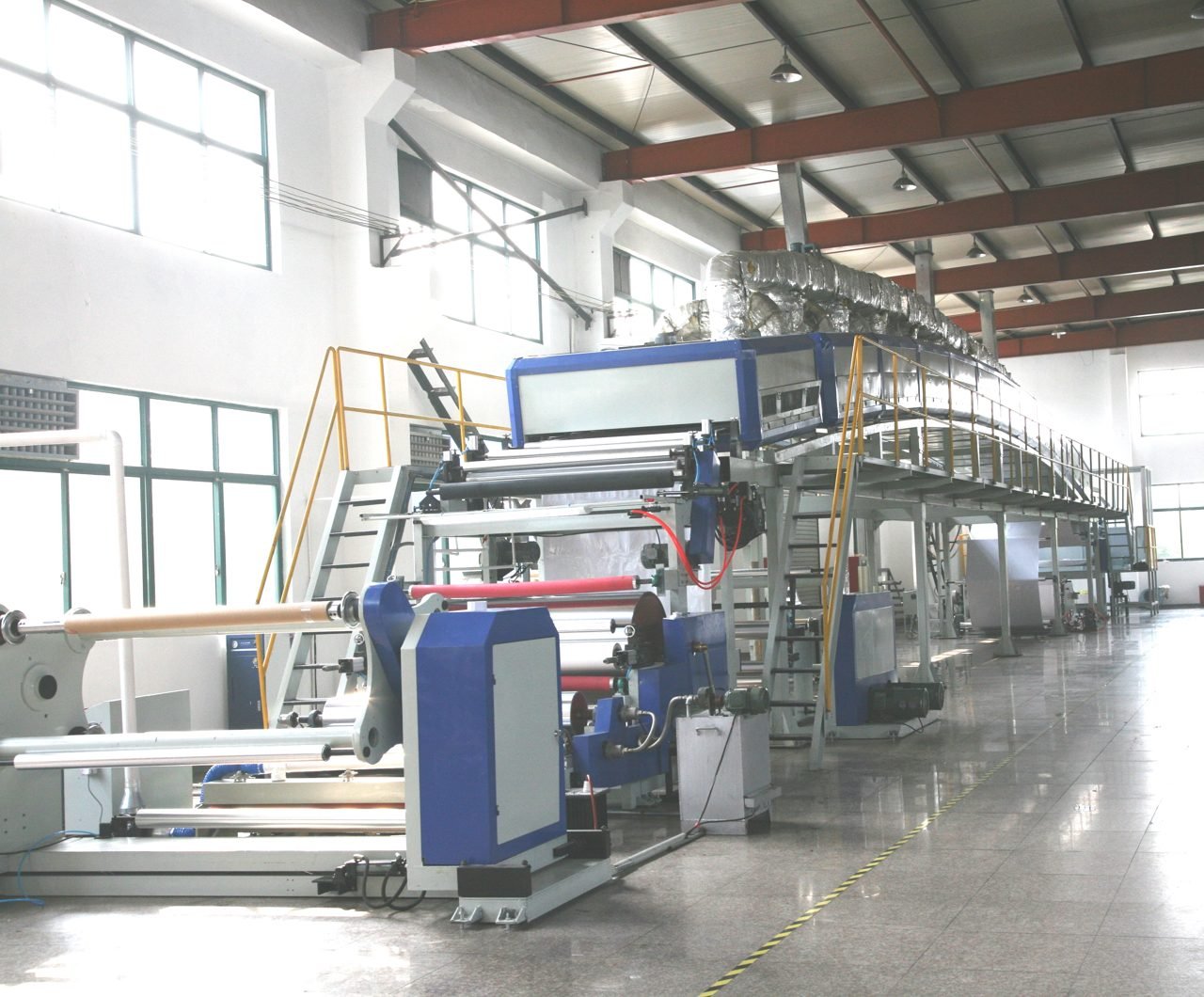 Long row of blue and white coating machinery with safety railings
